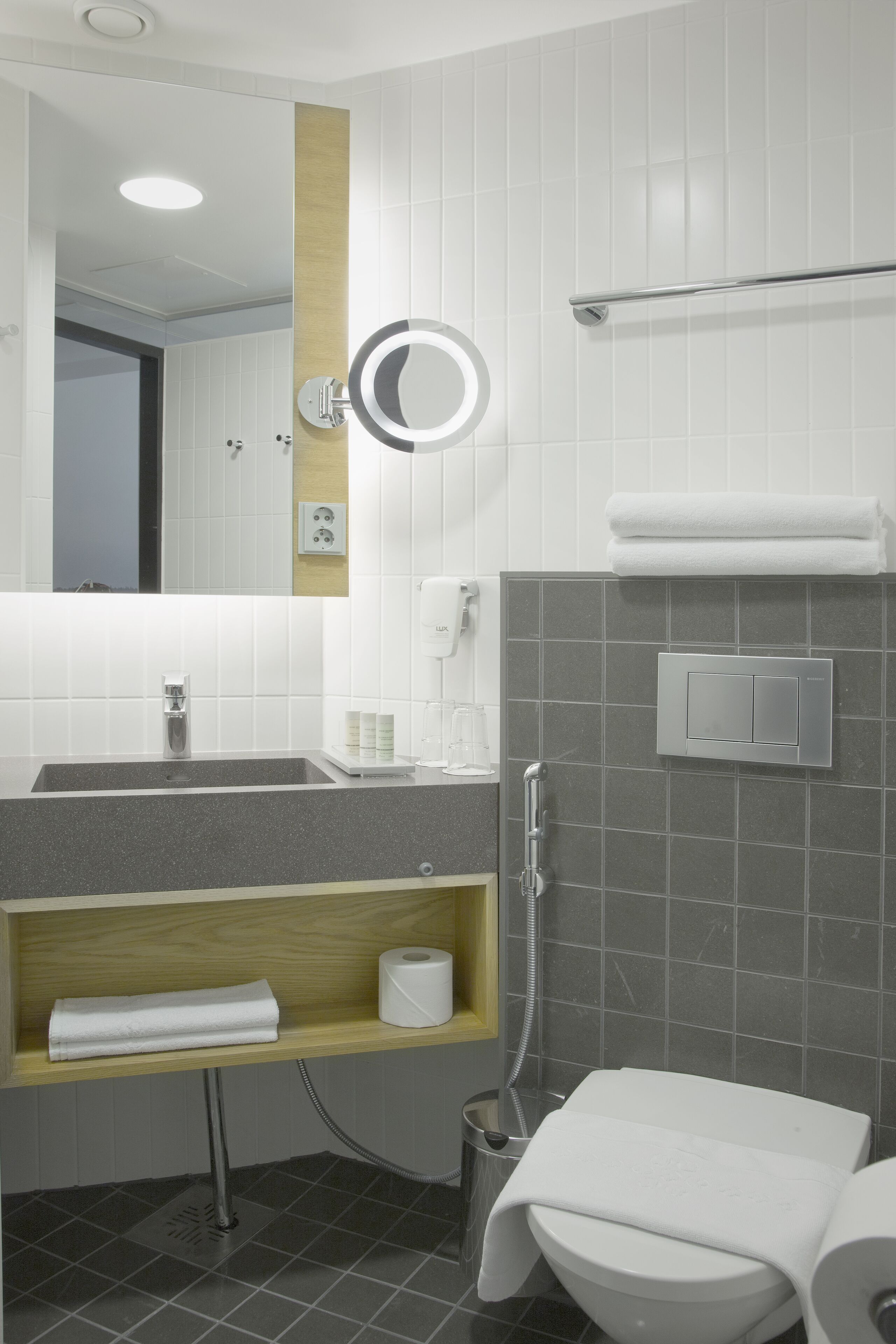 A modern bathroom with a sink, mirror, towel rack, and toilet.