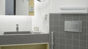 A modern bathroom with a sink, mirror, towel rack, and toilet.