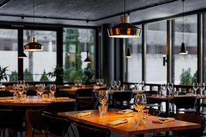 A restaurant with tables set for dining, large windows, and hanging pendant lights. - Radisson Blu Hotel, Espoo (Espoo)