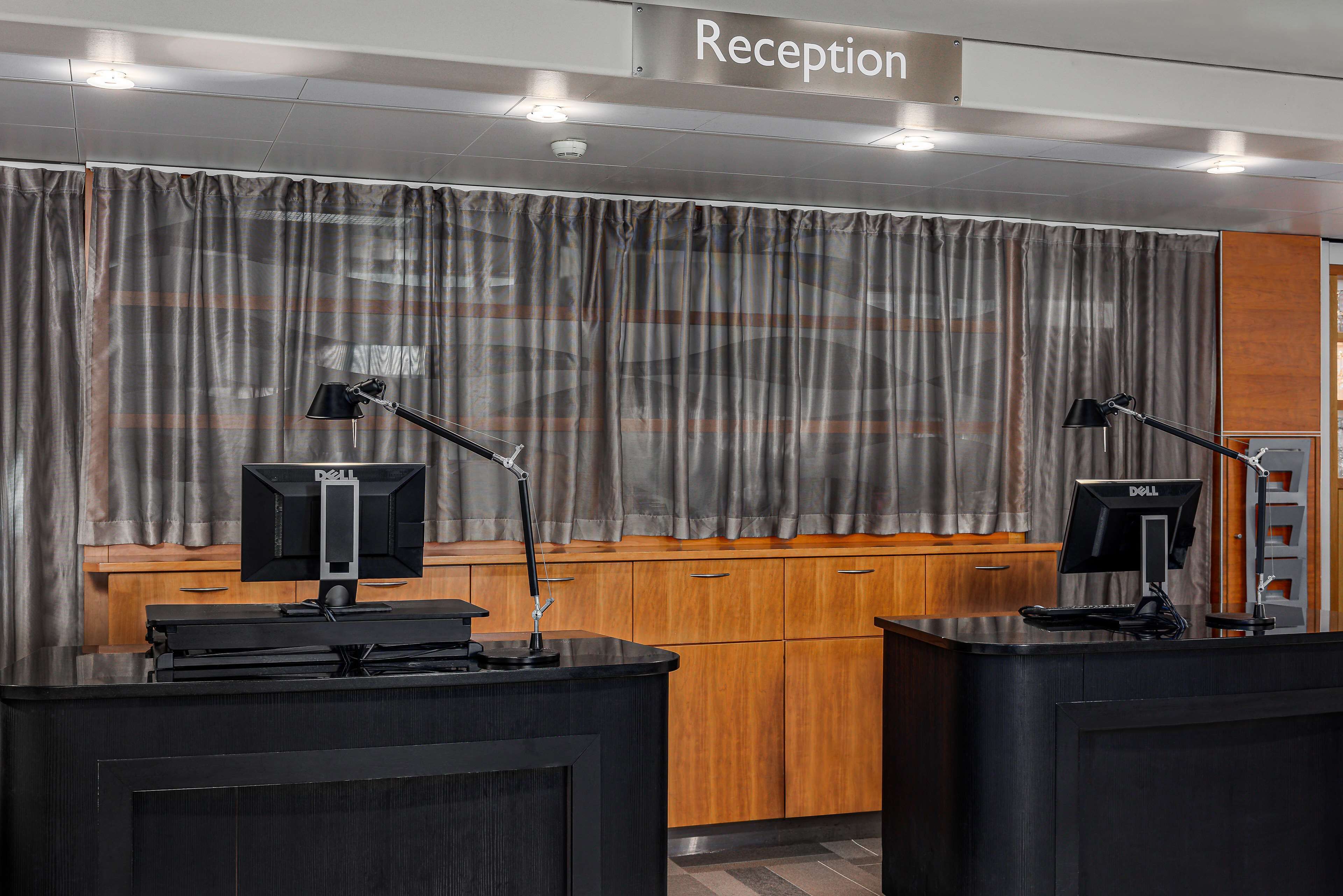 Zona de recepción con dos mostradores, armarios de madera y un letrero que indica la recepción.