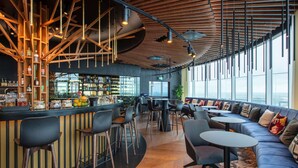 A modern bar area with a wooden ceiling, bar stools, and a seating area with sofas and tables. - Radisson Collection Hotel, Tallinn (Tallinn)