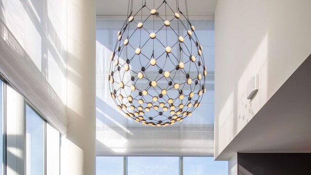 A modern living room with a large window, a round rug, two armchairs, a coffee table, and a unique spherical chandelier. - Radisson Collection Hotel, Tallinn (Tallinn)