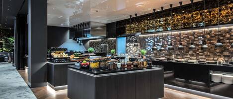 A modern kitchen with a marble floor, a central island with food items, and a patterned backsplash.