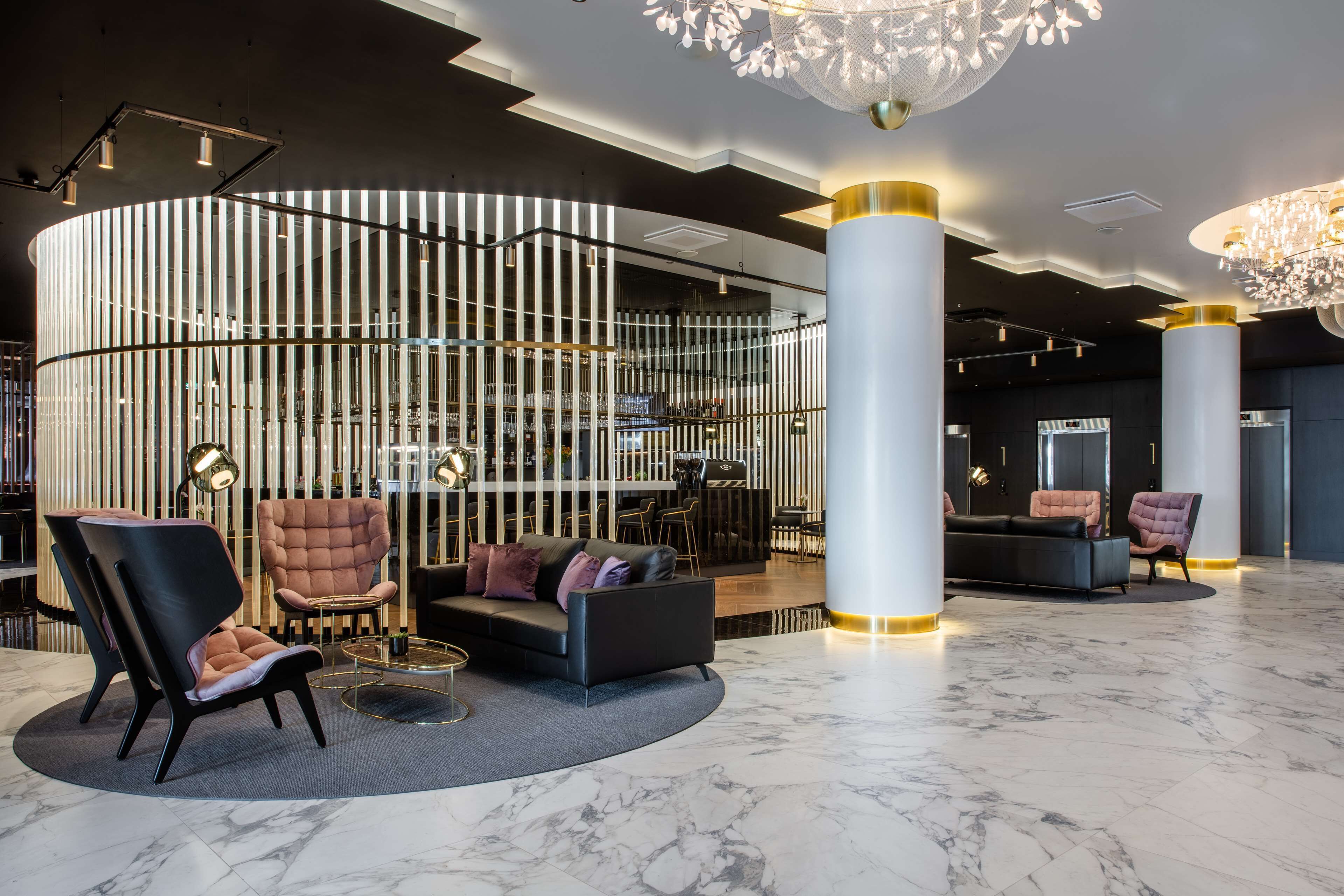Um lobby moderno com uma área de estar em curva, uma mesa de recepção e um pilar decorativo.
