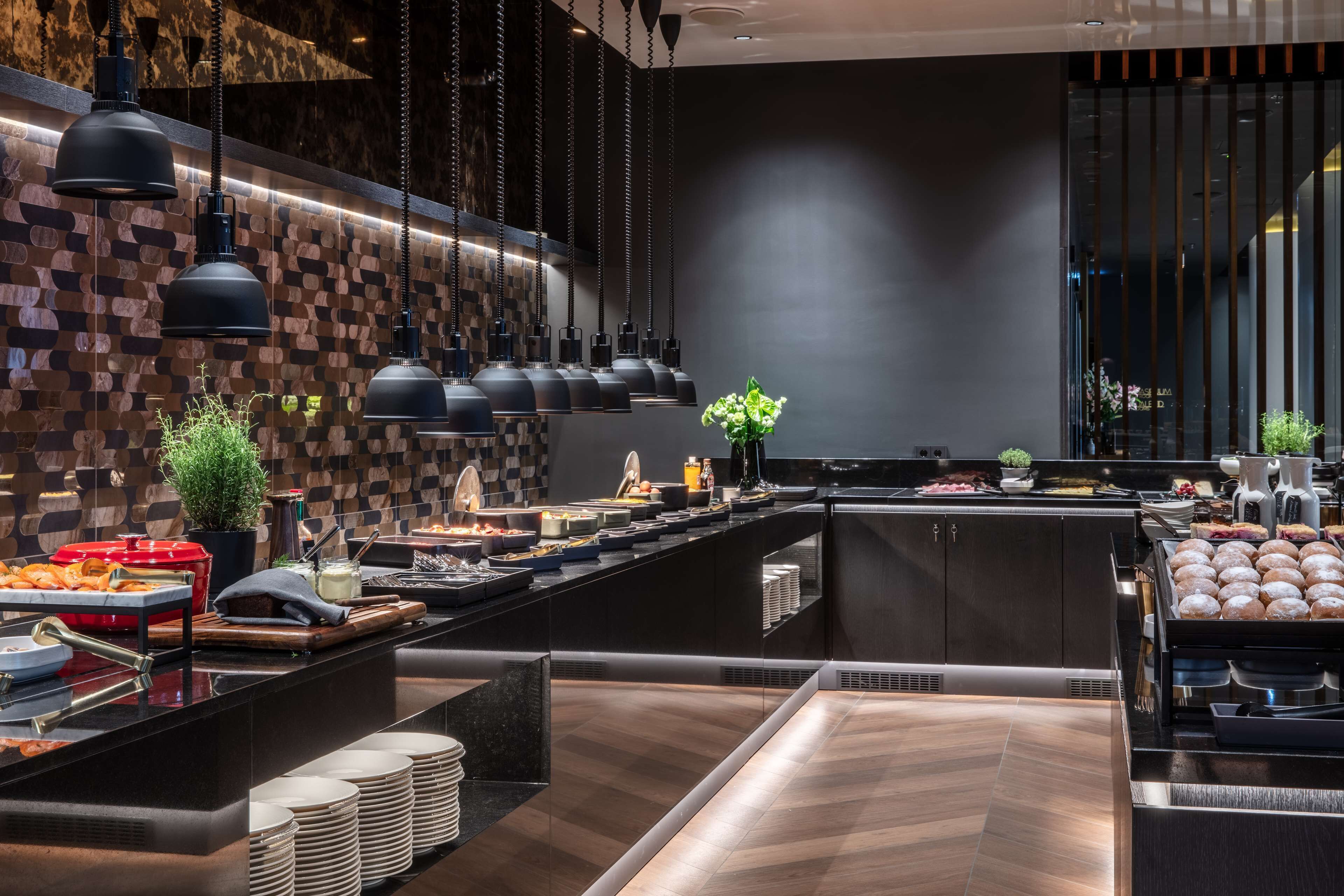 A modern buffet setup with multiple food stations, a central serving area, and hanging pendant lights.