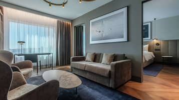 Un salon moderne avec un canapé, des fauteuils, une table basse et un grand tableau abstrait.