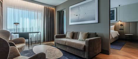 A modern living room with a sofa, armchairs, a coffee table, and a large abstract painting.