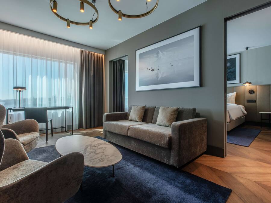 Un salon moderne avec un canapé, des fauteuils, une table basse et un grand tableau abstrait.