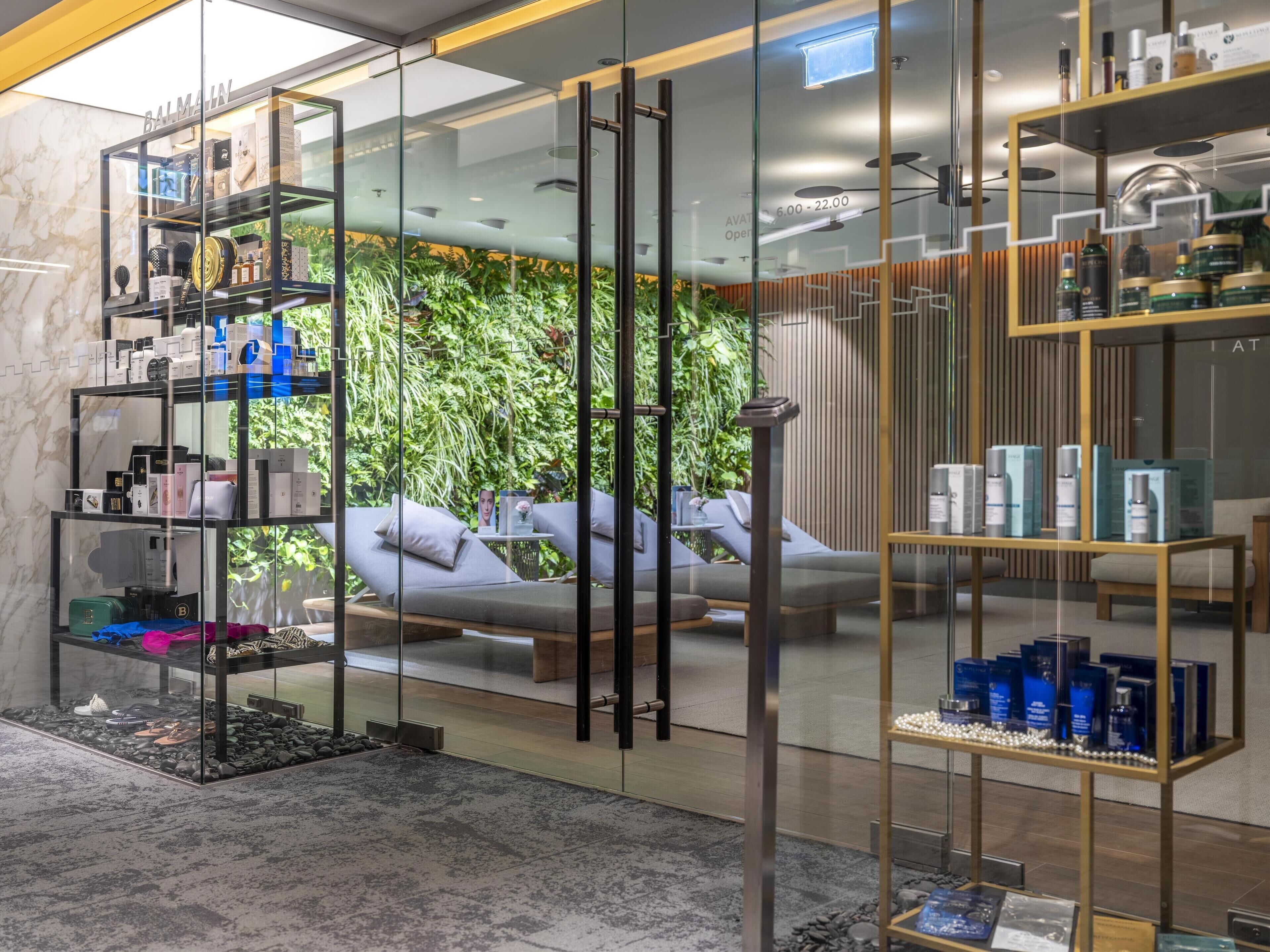A modern spa area with glass partitions, a relaxation area with a sofa, and shelves displaying various products.