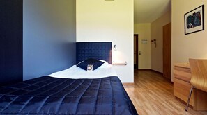 Un dormitorio ordenado con cama, mesita de noche y una silla.