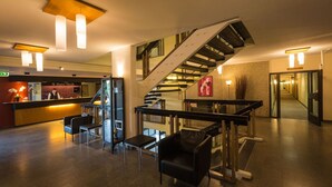 A hotel lobby with a reception desk, seating area, staircase, and modern lighting fixtures. - Q Hotel Växjö (Vaxjo)