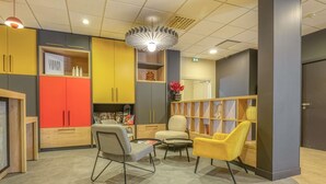 Un vestíbul modern amb zona de seients, armaris de fusta i una làmpada decorativa al sostre.