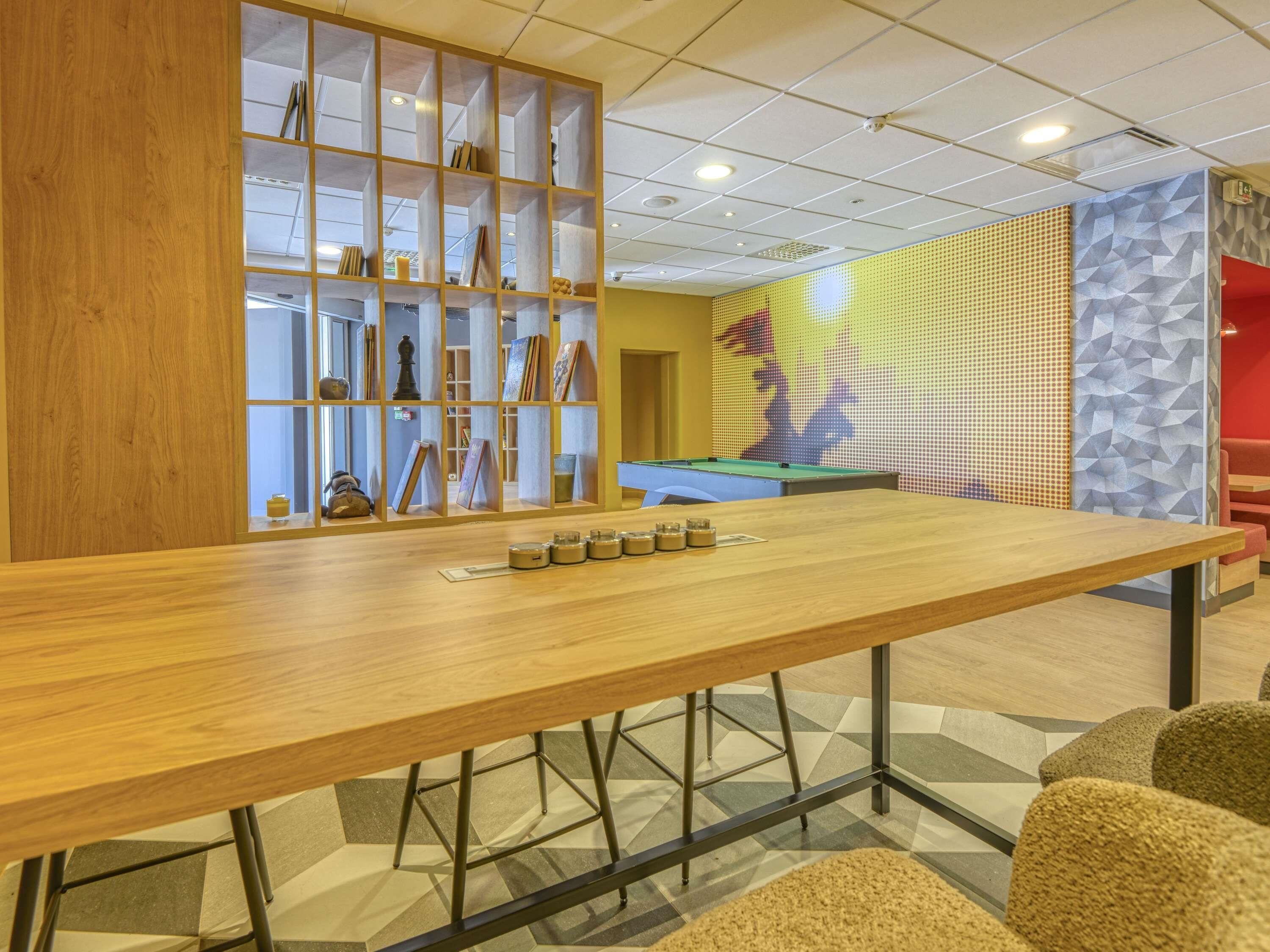 Una mesa de billar, un mostrador de bar de madera y una mesa de billar en una sala con paredes de diseño geométrico.