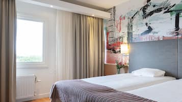 Relax in a stylish room with a large bed, vibrant mural, and a window with curtains.