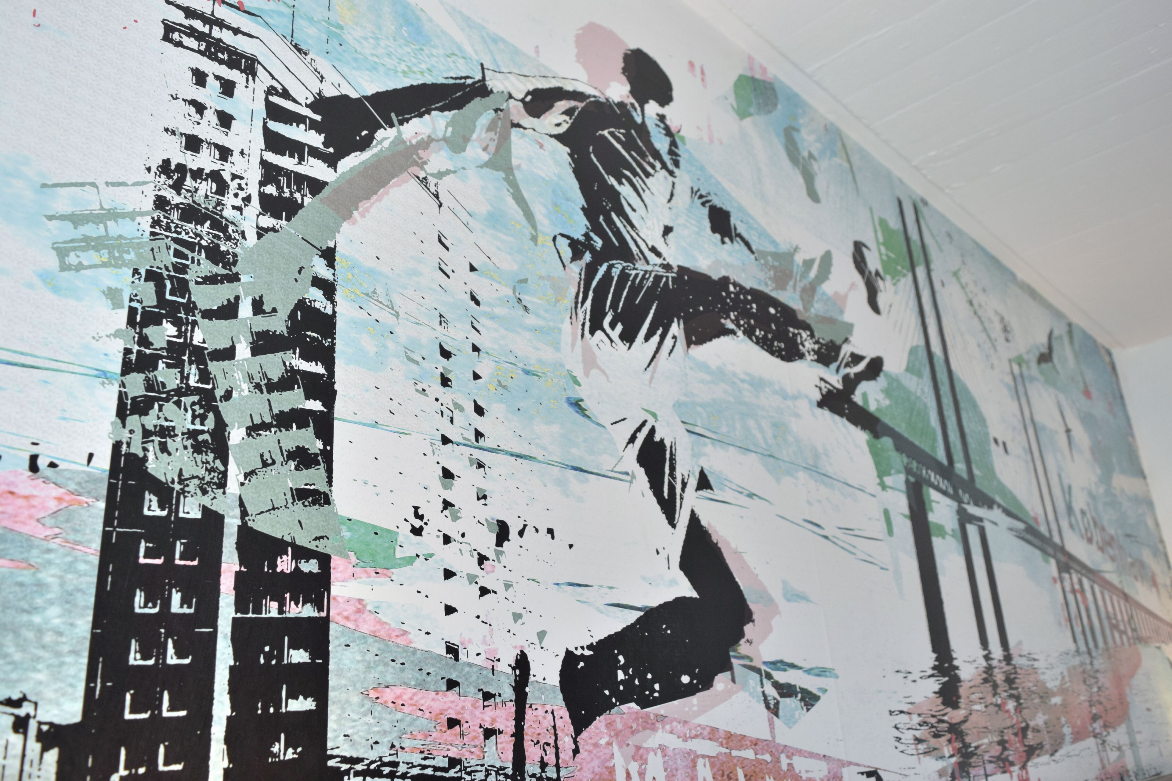 A large mural with abstract and graffiti art, featuring a figure in motion and a building structure.