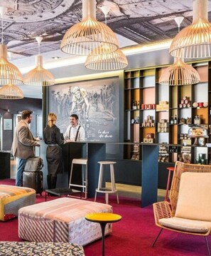A hotel lobby with a reception desk, seating area, and a mural on the wall. - Novotel Lille Centre Gares (Lille)