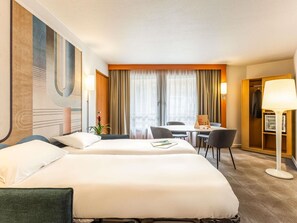 A hotel room with two beds, a desk, chairs, a lamp, and a wardrobe. - Novotel Lille Centre Gares (Lille)