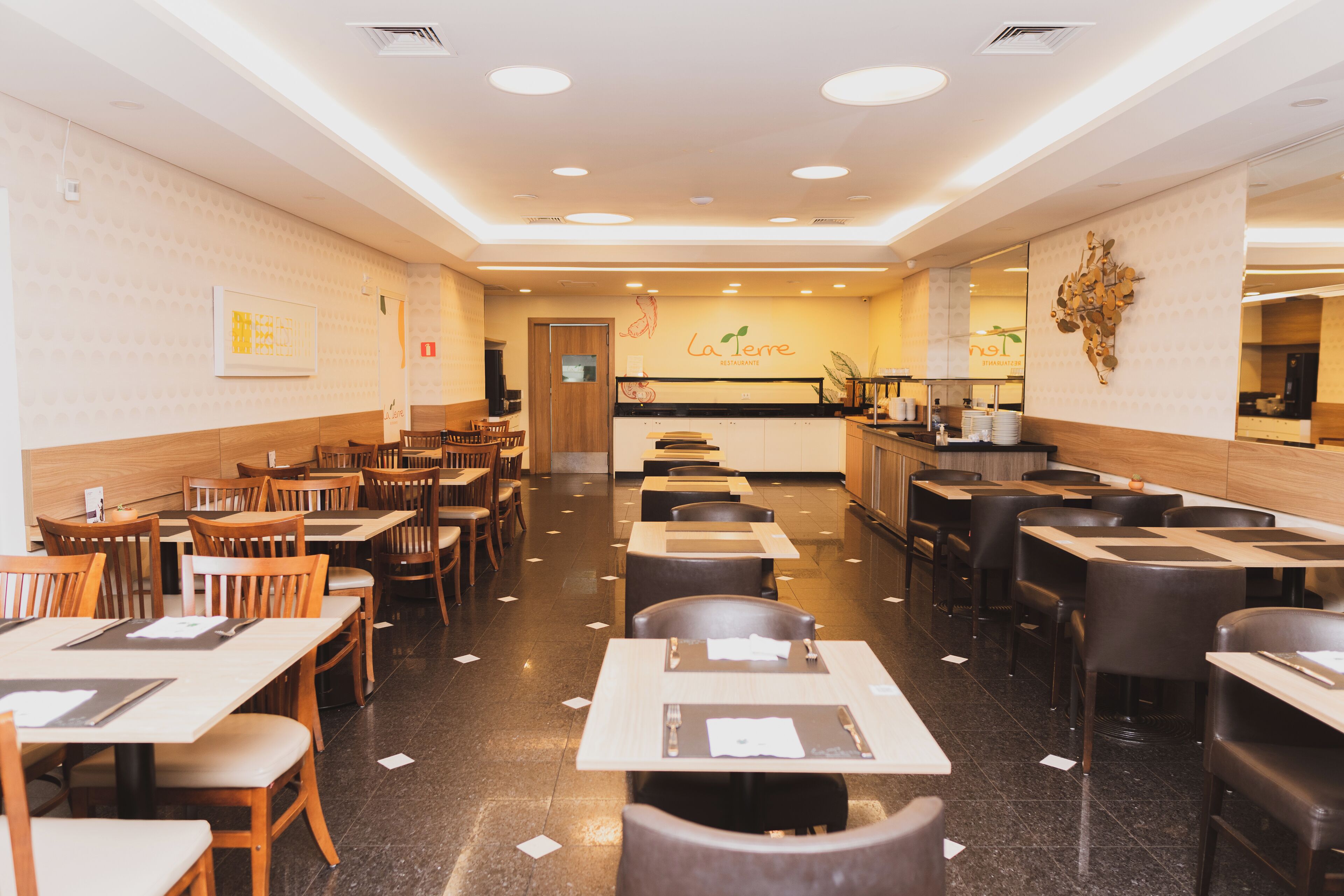 Un restaurante con varias mesas y sillas, una barra con un menú y una pared con un logotipo.