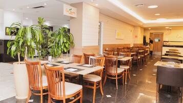 Un restaurante con mesas y sillas de madera, plantas en macetas y un letrero que dice 'La Terre'.