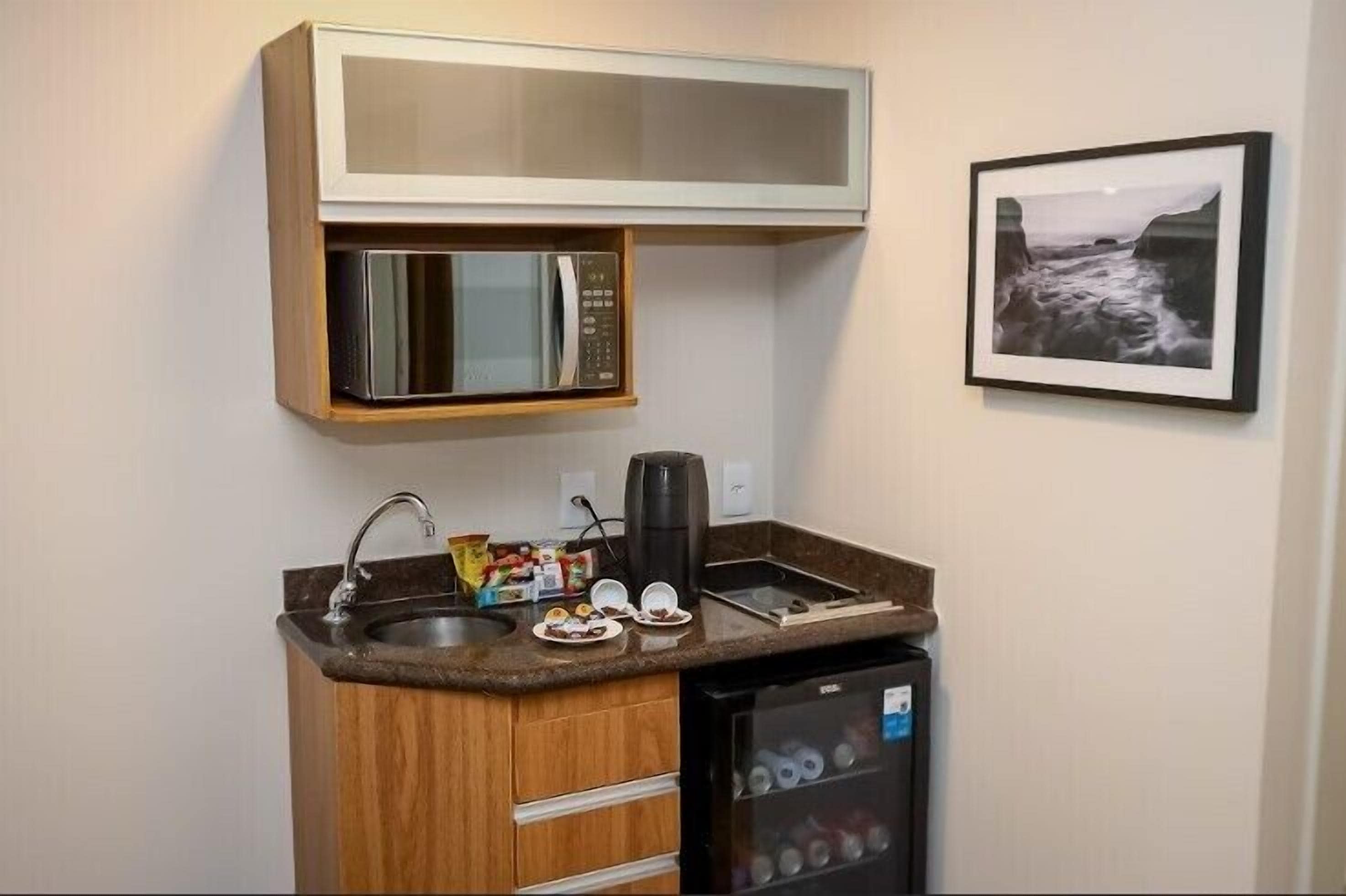 Een kleine keuken met een magnetron, koffiezetapparaat en een minibar.