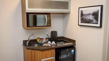 Een kleine keuken met een magnetron, koffiezetapparaat en een minibar.