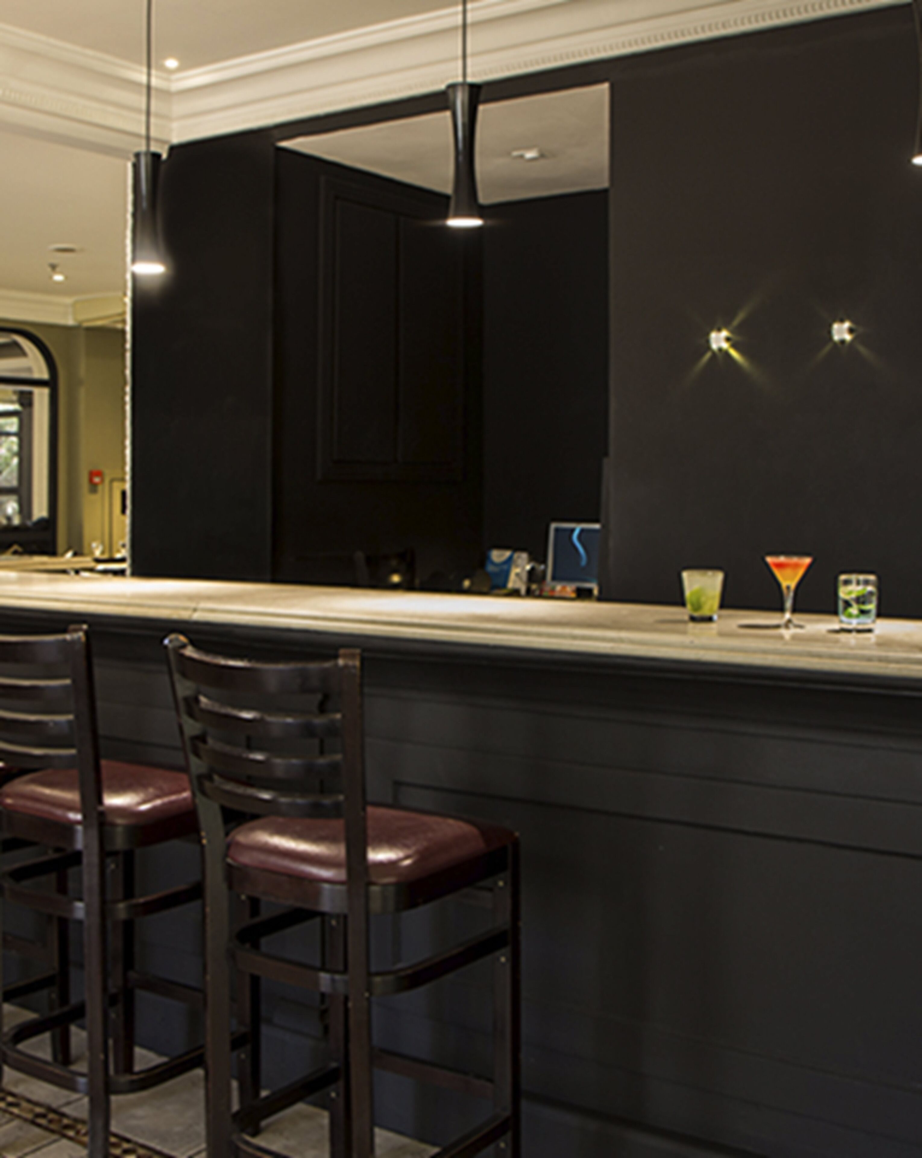 A bar area with dark wooden chairs, a counter, and a mirror.