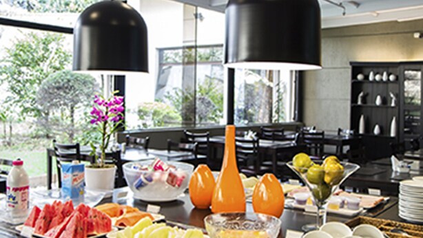 Una mesa de buffet con diversos alimentos y bebidas, incluyendo sandía, frutas y un tazón de cereal.