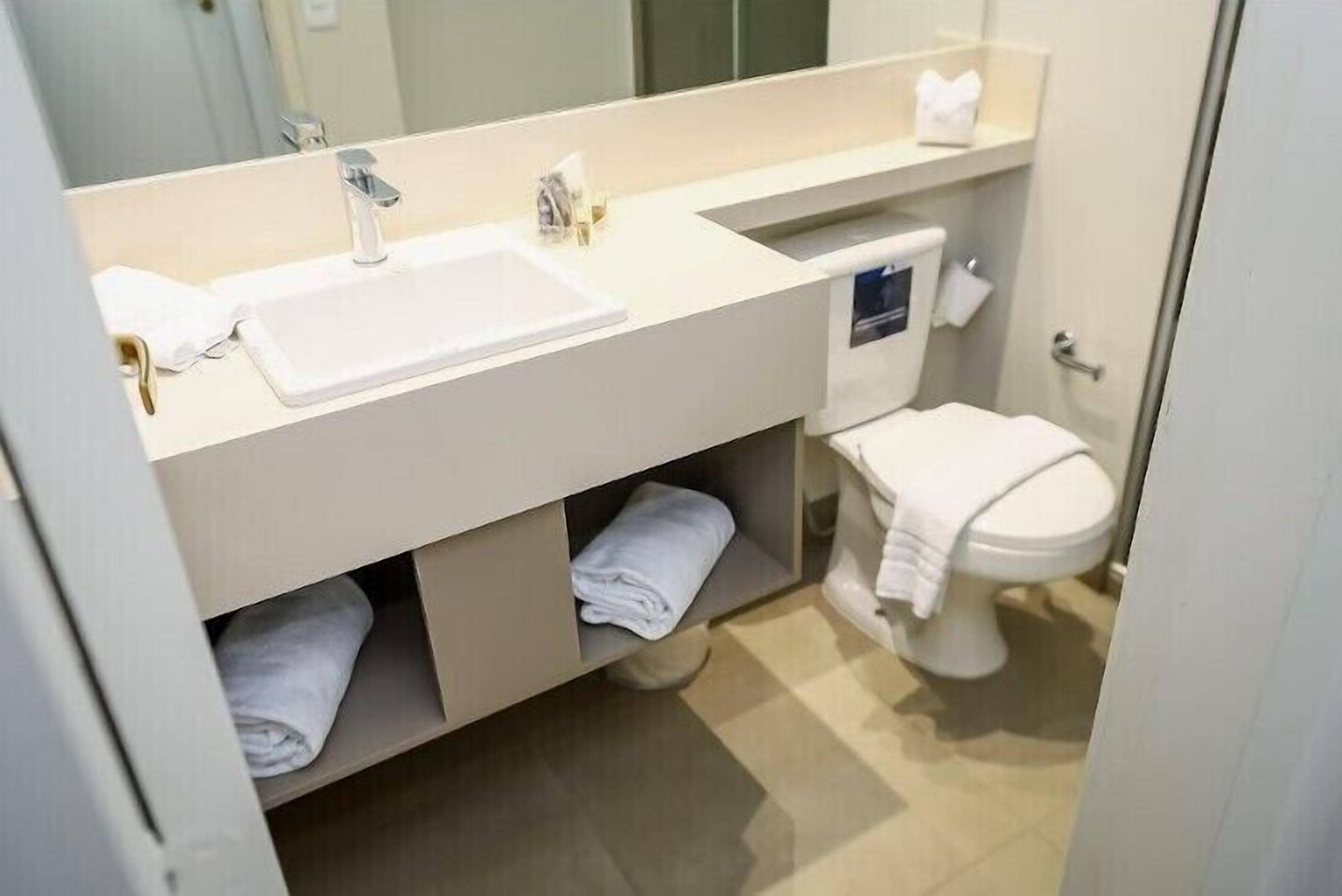 Een moderne badkamer met een wit wastafel, twee kraanwerk, een toilet en een handdoekhouder.