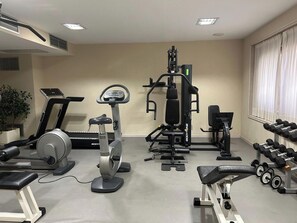 Un gimnasio con máquinas de cardio, equipo de levantamiento de pesas y mancuernas.