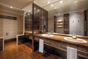 Un baño moderno con dos lavamanos, un espejo grande y una cabina de ducha de vidrio.