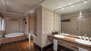A modern bathroom with a large bathtub, a walk-in shower, and a vanity with two sinks and a large mirror.