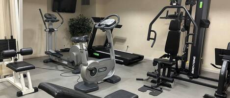 A gym with various exercise equipment including treadmills, a bench press, and weight machines.