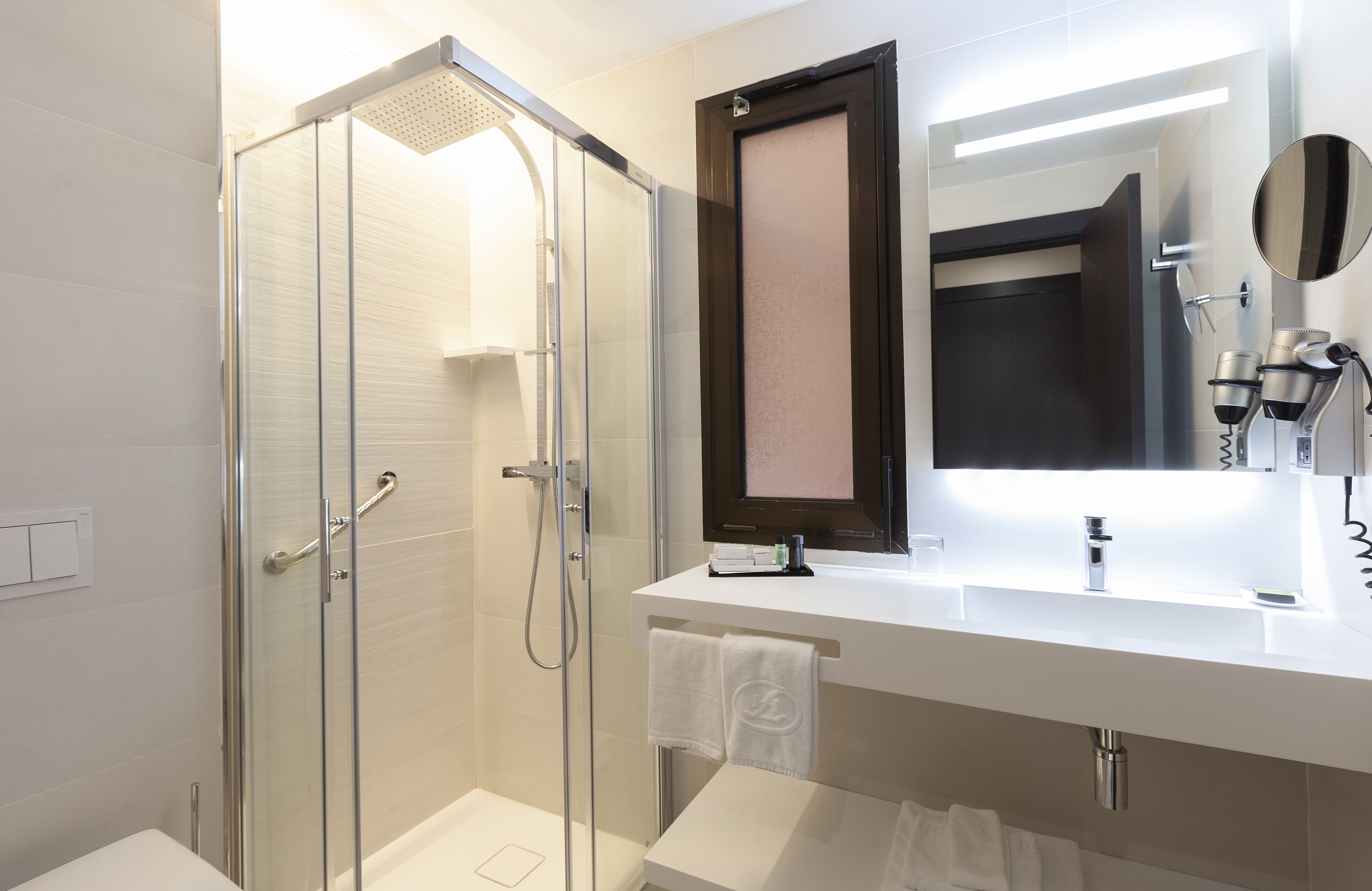 A modern bathroom with a glass-enclosed shower, a white sink with a mirror, and a towel rack.