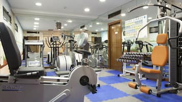 Un gimnasio con diverso equipo de ejercicio, que incluye cintas de correr, máquinas de pesas y mancuernas.