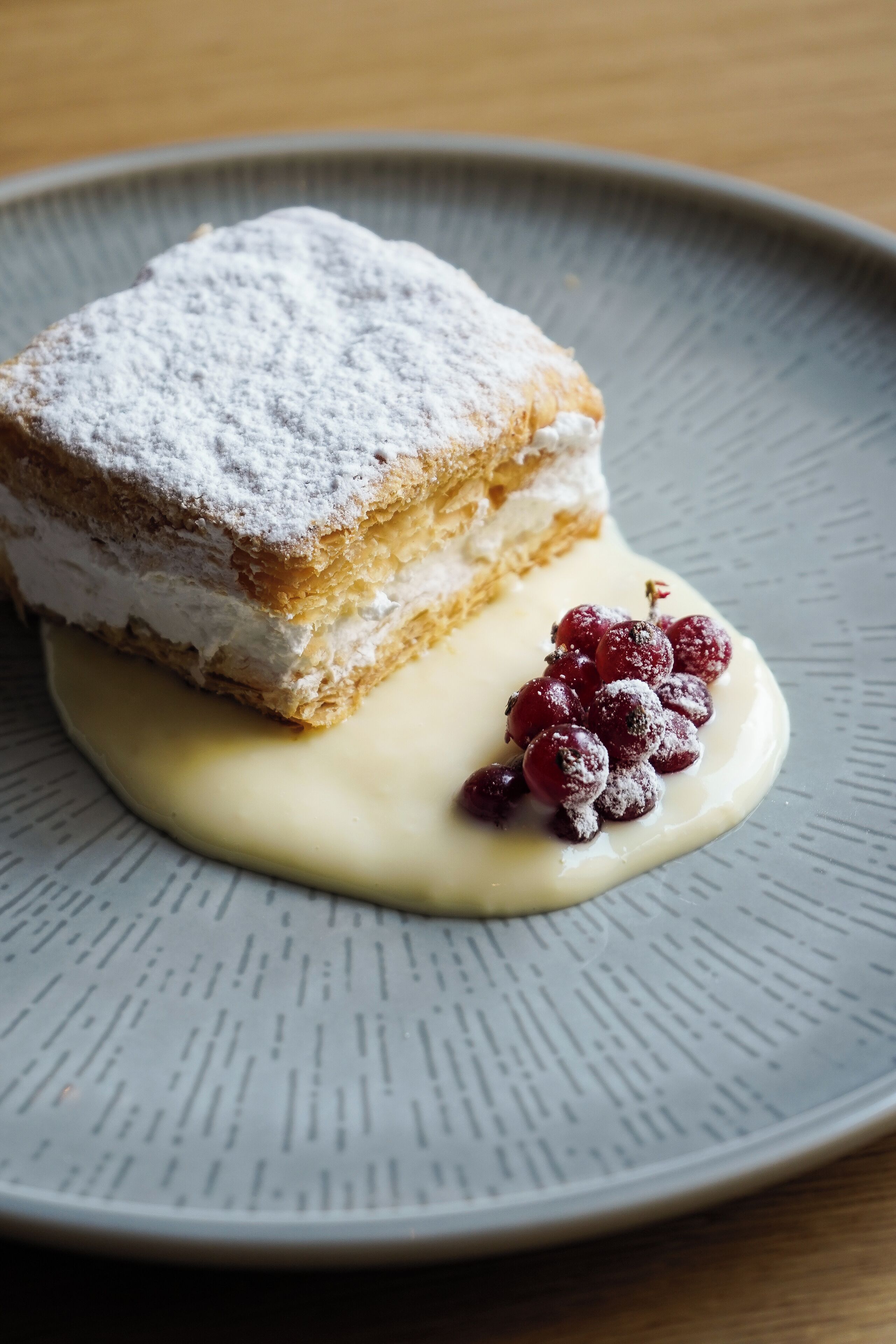 A dessert with a powdered topping and berries on a plate.
