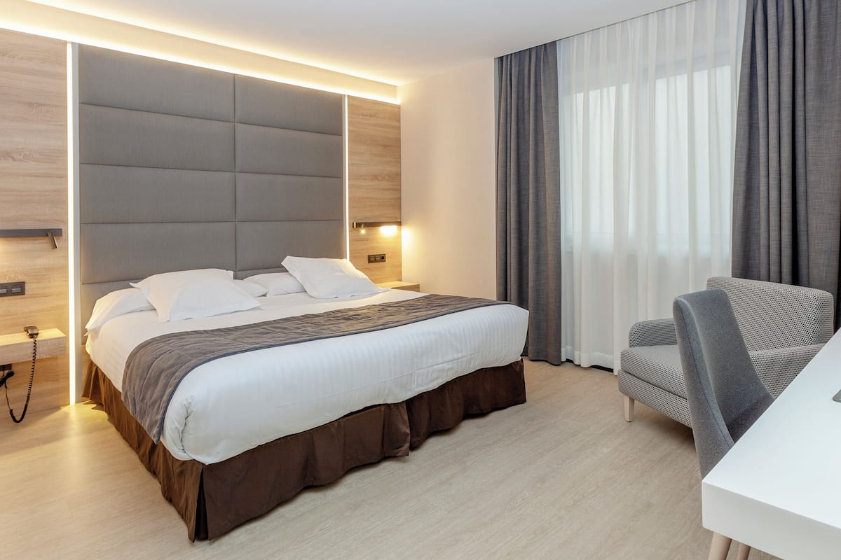 Moderni hotellihuone, jossa on suuri sänky, työpöytä ja tuoli.