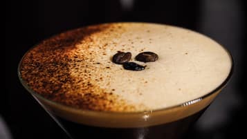 Una copa de martini con espuma arriba y granos de café en el borde.