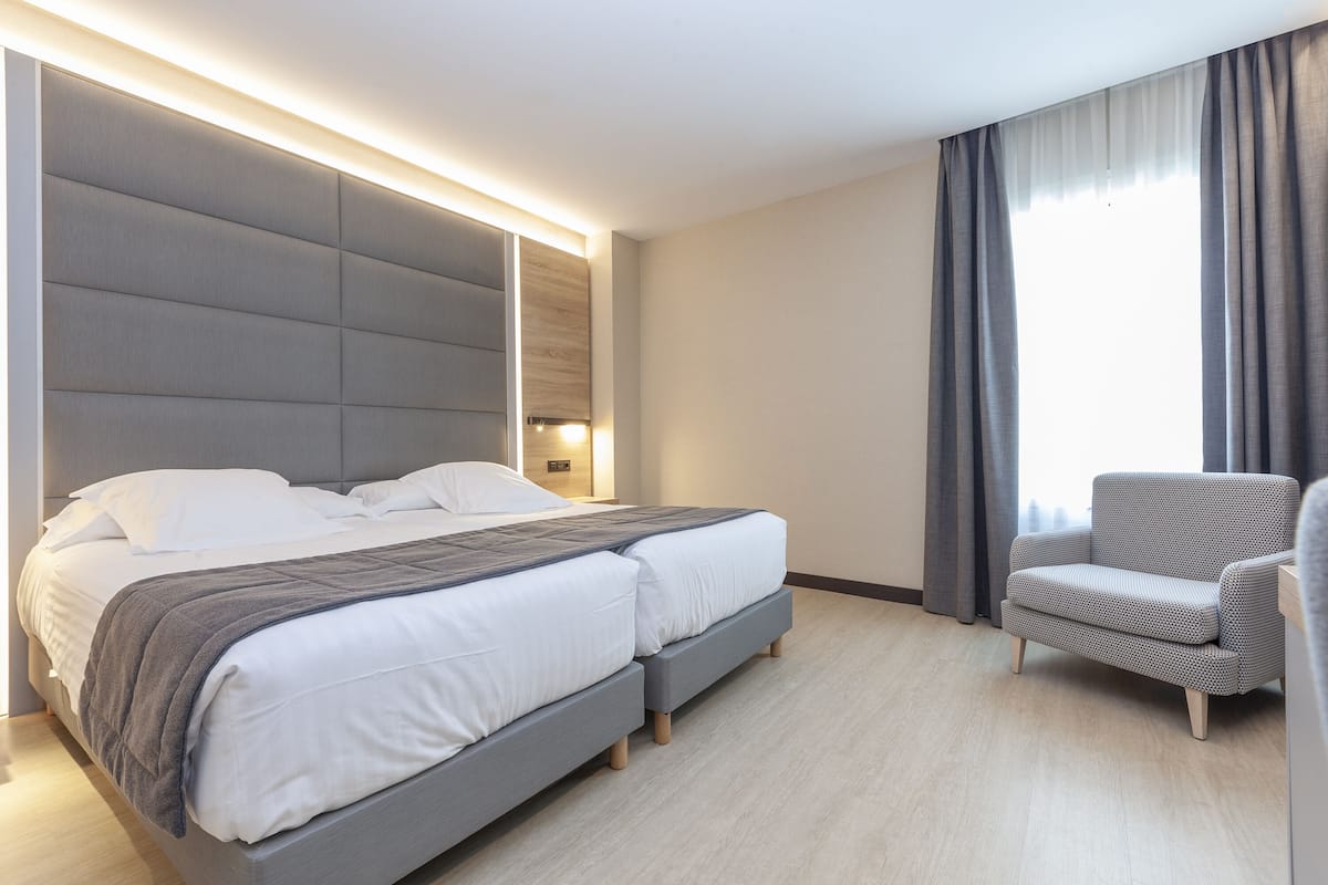 Moderni hotellihuone, jossa on suuri sänky, oleskelualue ja näkymä ulos.