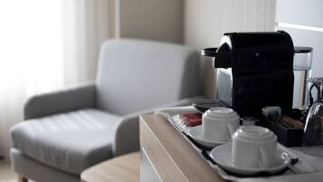 Habitación de hotel con comedor que incluye una cafetera, dos tazas blancas y una bandeja con un paquete de galletas.