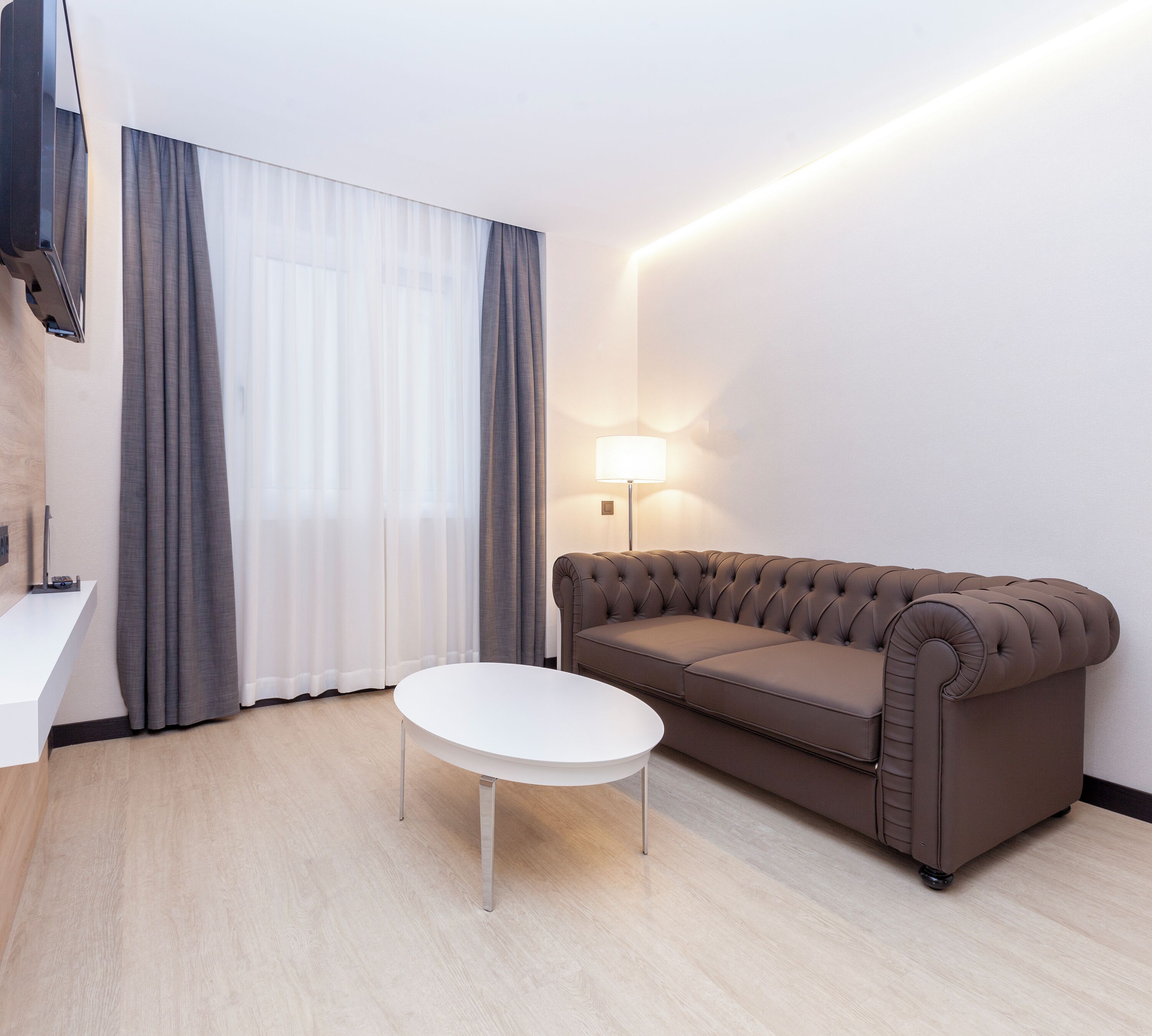 Un salon moderne avec un canapé beige, une table basse blanche et une lampe.