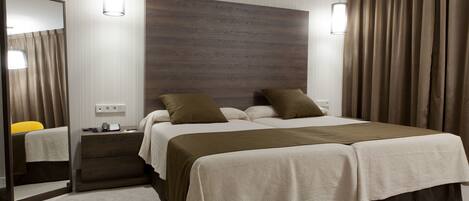 A double bed with a wooden headboard, a bedside table with a lamp, and a mirror.
