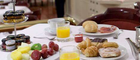 Un bufé de desayuno con platos de pasteles, frutas y zumo.