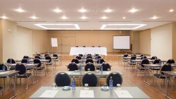 A conference room with tables, chairs, water bottles, and a whiteboard.