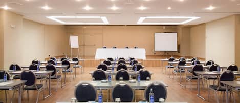 Un salón de conferencias con mesas, sillas, botellas de agua y una pizarra.