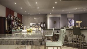 A modern kitchen with a marble countertop, bar area, and seating. - Hotel Zentral Parque (Valladolid)