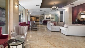 A spacious lobby with a marble floor, modern furniture, and a chandelier. - Hotel Zentral Parque (Valladolid)
