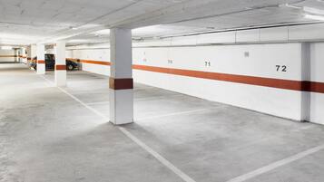 Un parking propre et vide, avec des murs blancs et des rayures orange, et des places de stationnement numérotées.
