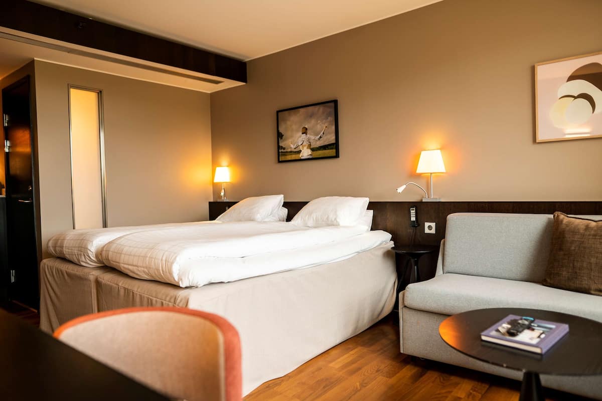 Ein Hotelzimmer mit einem Bett, einer Couch, einem kleinen Tisch und zwei Nachttischlampen.