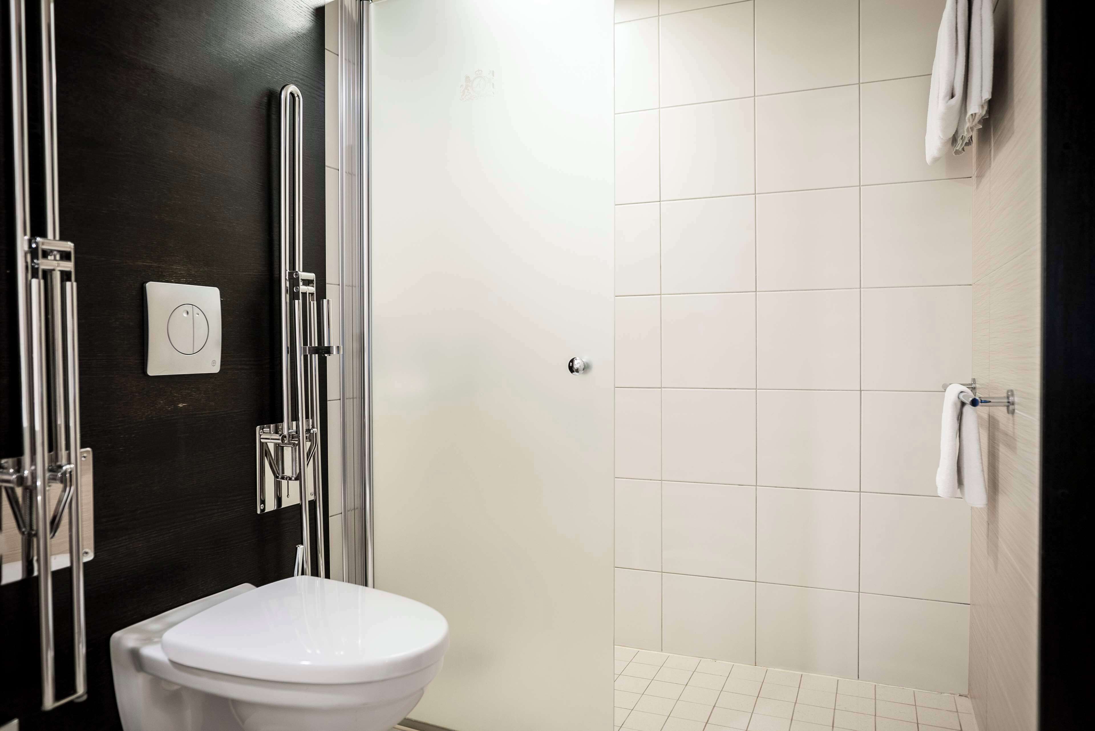 Un baño moderno con inodoro blanco, ducha con puerta de vidrio y un toallero.