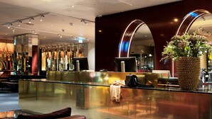 Eine moderne Hotelhalle mit Glastrennwand, Sitzgelegenheiten und einer großen Pflanze in einem Topf.